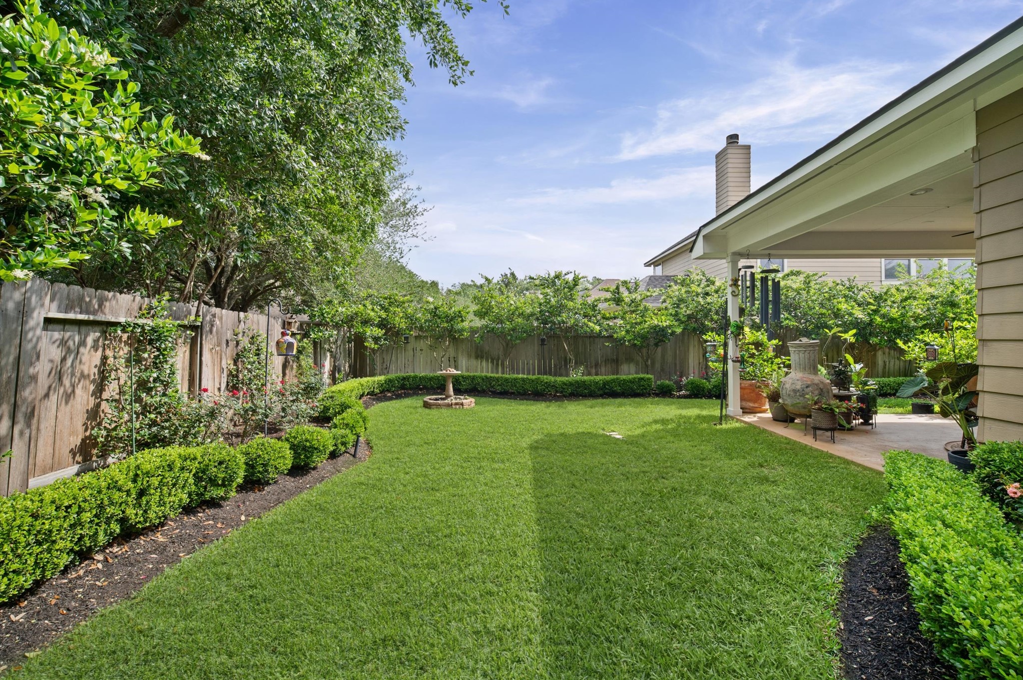 1603 Claytons Bend Court Spring, TX 77386 - Photo 31 of 38 This backyard features a well-maintained lawn with lush greenery and a wooden fence for privacy. There's a cozy covered patio, perfect for outdoor relaxation and entertaining.