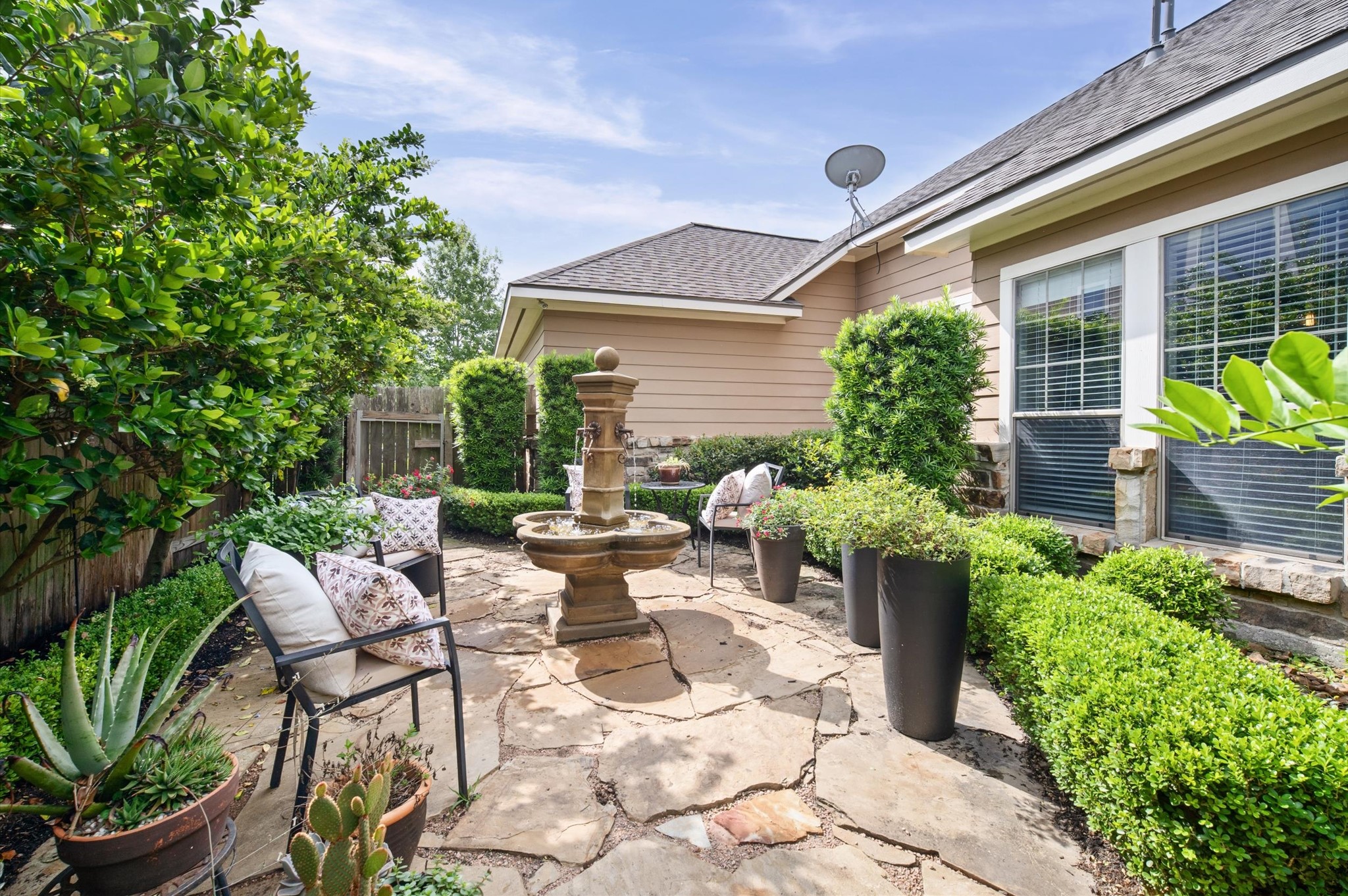 1603 Claytons Bend Court Spring, TX 77386 - Photo 33 of 38 Charming backyard patio with a stone pathway, surrounded by lush greenery and neatly trimmed hedges. Features a central fountain, comfortable seating, and decorative planters, creating a serene outdoor retreat.