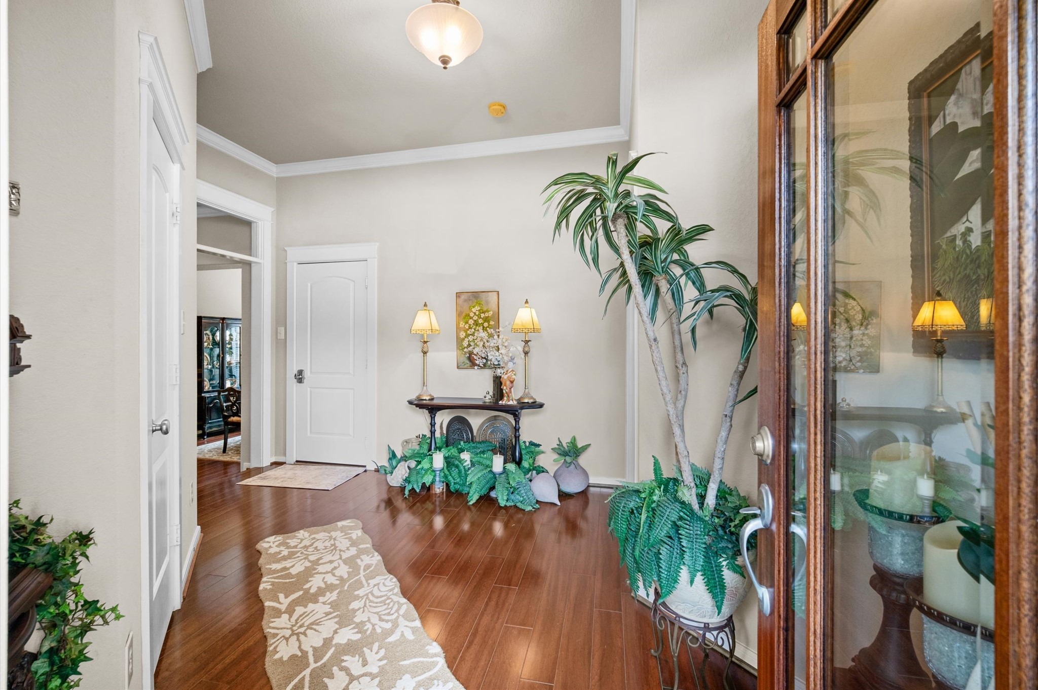 1603 Claytons Bend Court Spring, TX 77386 - Photo 5 of 38 This welcoming entryway features warm wood flooring, elegant decor, and soft lighting. There's a decorative table with lamps and greenery, and a glass-paneled door adds charm and natural light.