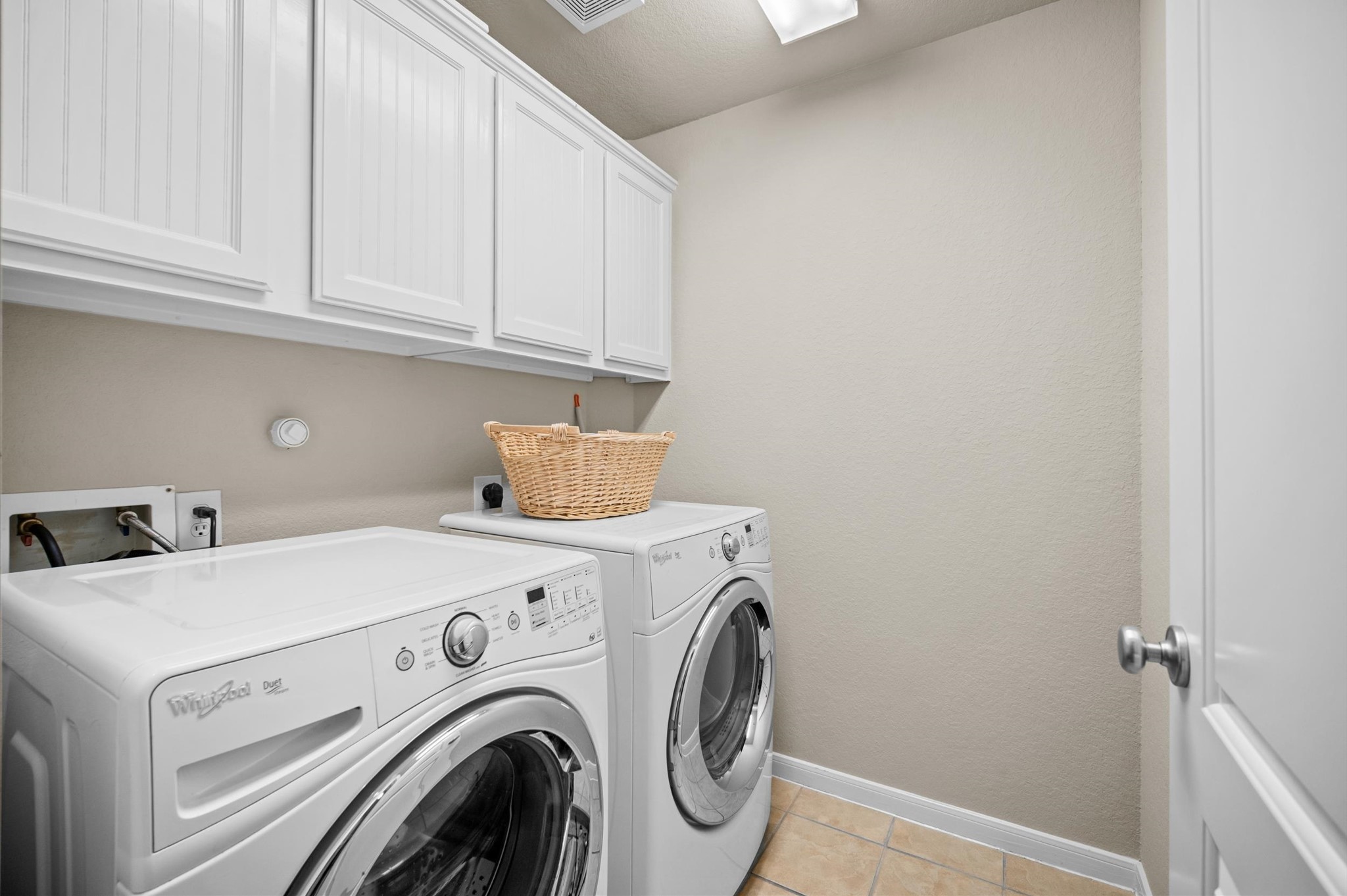 1603 Claytons Bend Court Spring, TX 77386 - Photo 9 of 38 This photo shows a well-lit laundry room with a modern washer and dryer set, white cabinetry for storage, and a tile floor.