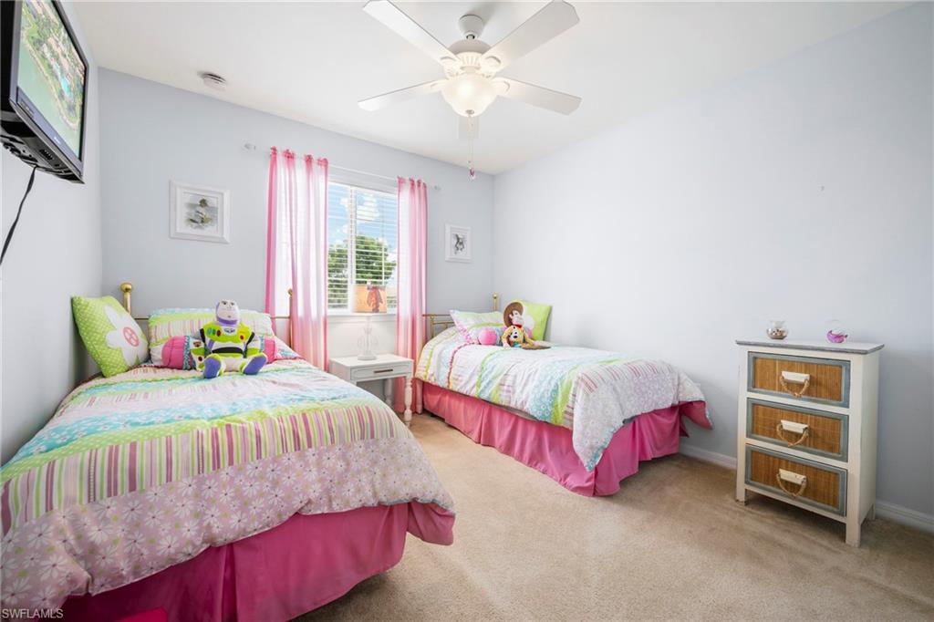 3916 Cherrybrook Loop Fort Myers, FL 33966 - Photo 18 of 31 Bedroom featuring light blue walls, window with blinds and pink sheer curtains, beige carpet flooring, and a ceiling fan with integrated lighting