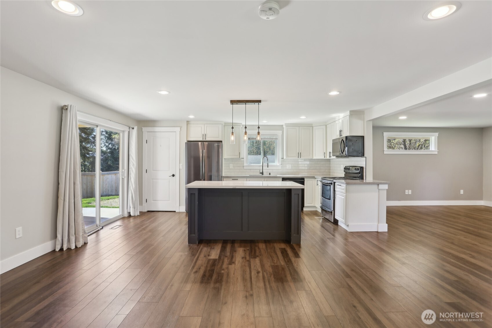27713 Webster Road East Graham, WA 98338 - Photo 13 of 39 a large kitchen with a center island wooden floor stainless steel appliances and a window