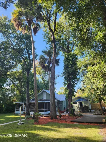a view of house with swimming pool and trees in the background