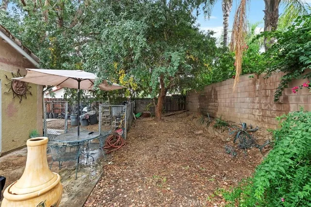 a view of a patio with table and chairs potted plants and a large tree