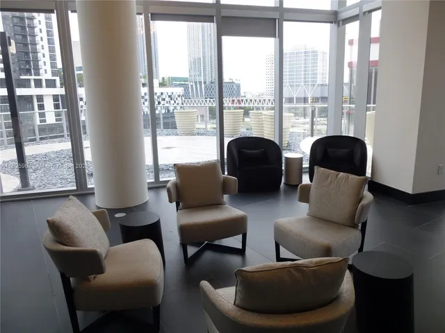 a living room with furniture a flat screen tv and a floor to ceiling window