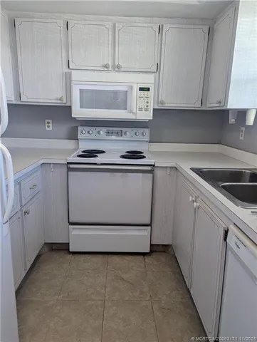 a kitchen with white cabinets and white appliances