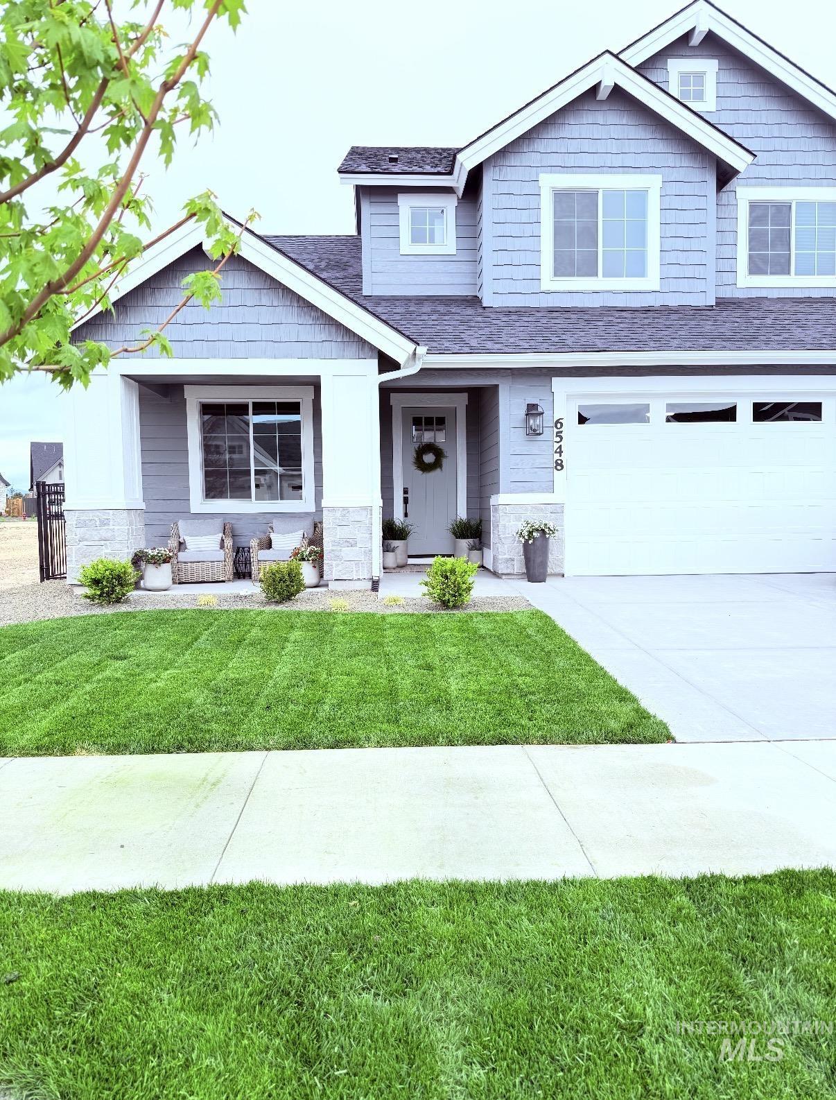 6548 South Utmost Lane Meridian, ID 83642 - Photo 2 of 3 Craftsman inspired home featuring stone siding, a front lawn, driveway, a garage, and roof with shingles