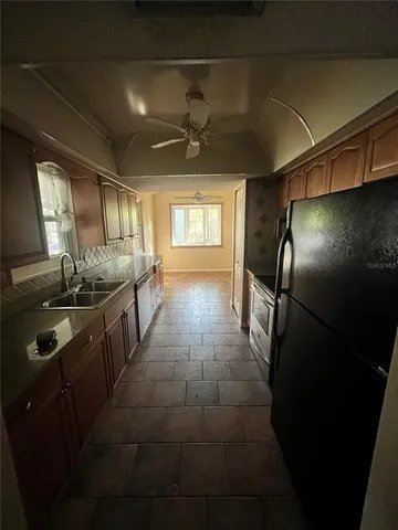 a kitchen with stainless steel appliances granite countertop a sink a stove a refrigerator a washer dryer and a dining table