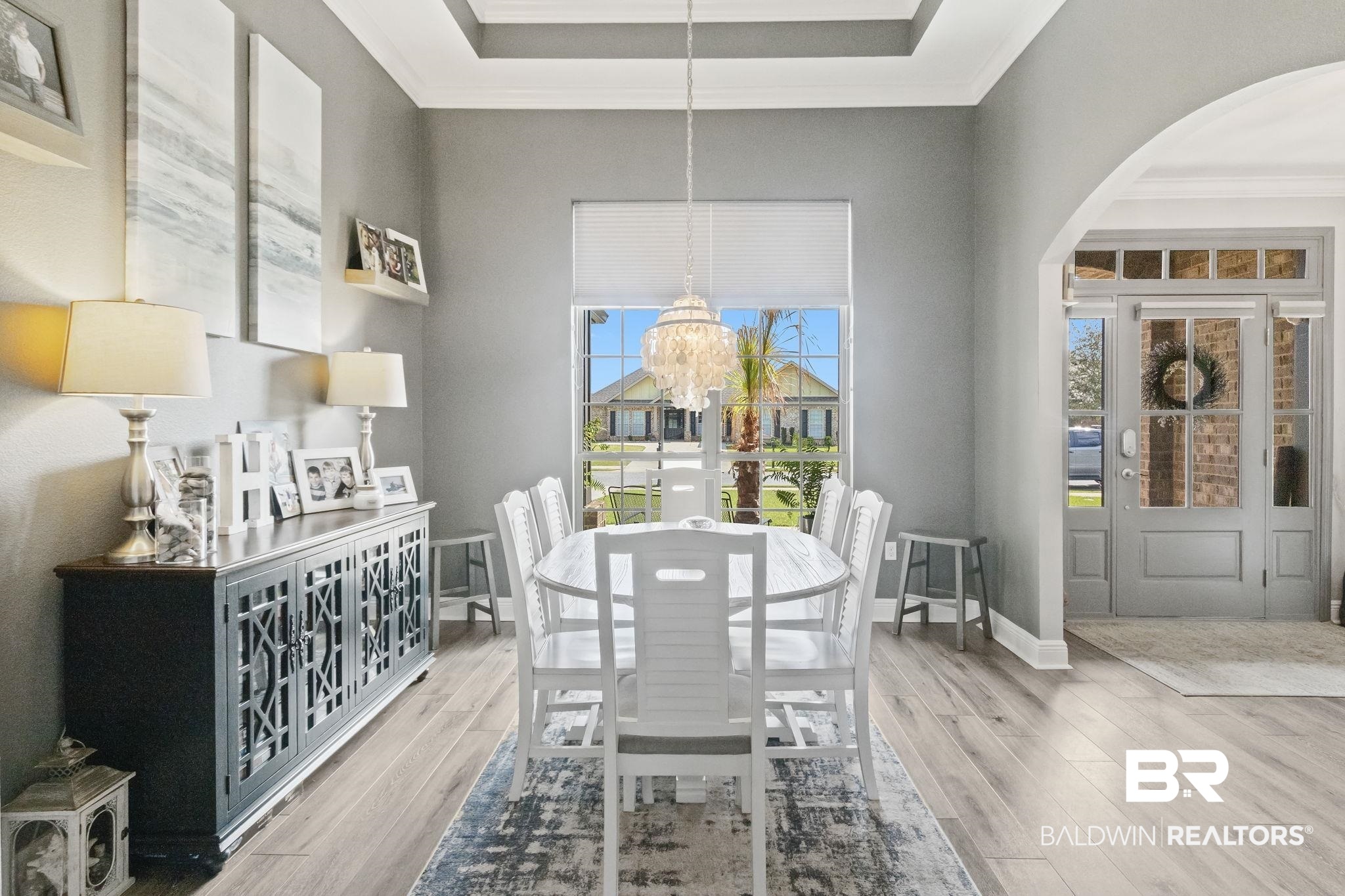 7051 Rocky Rd Loop Gulf Shores, AL 36542 - Photo 13 of 27 Dining area featuring a raised ceiling, ornamental molding, wood finished floors, an inviting chandelier, and baseboards