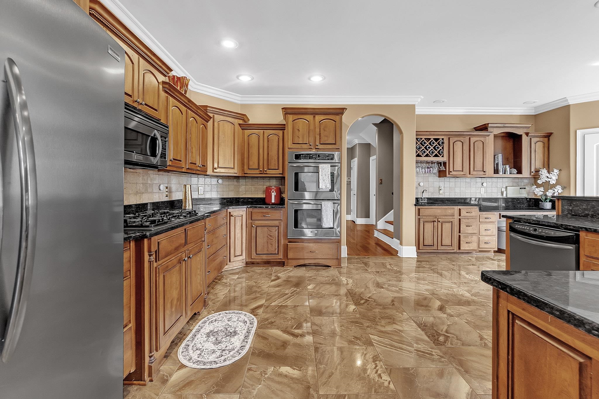 649 Ridge Springs Road Collierville, TN 38017 - Photo 12 of 38 Kitchen featuring wood cabinetry, dark countertops, a stainless steel refrigerator, double wall ovens, and stone tile flooring
