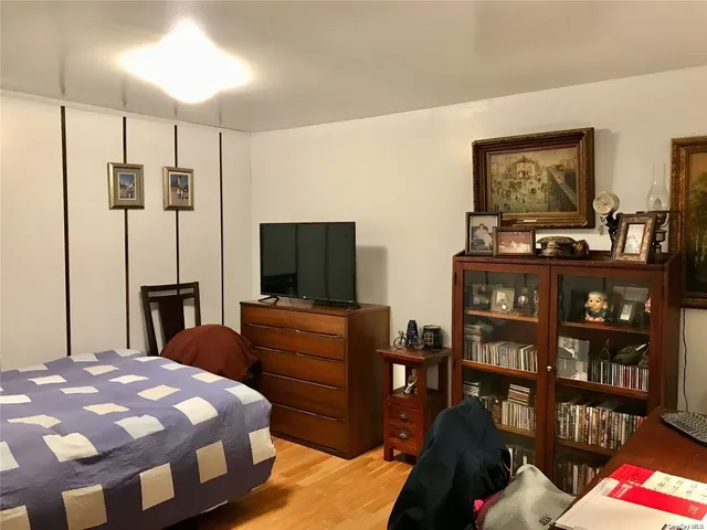a bedroom with a bed a dresser and a flat screen tv