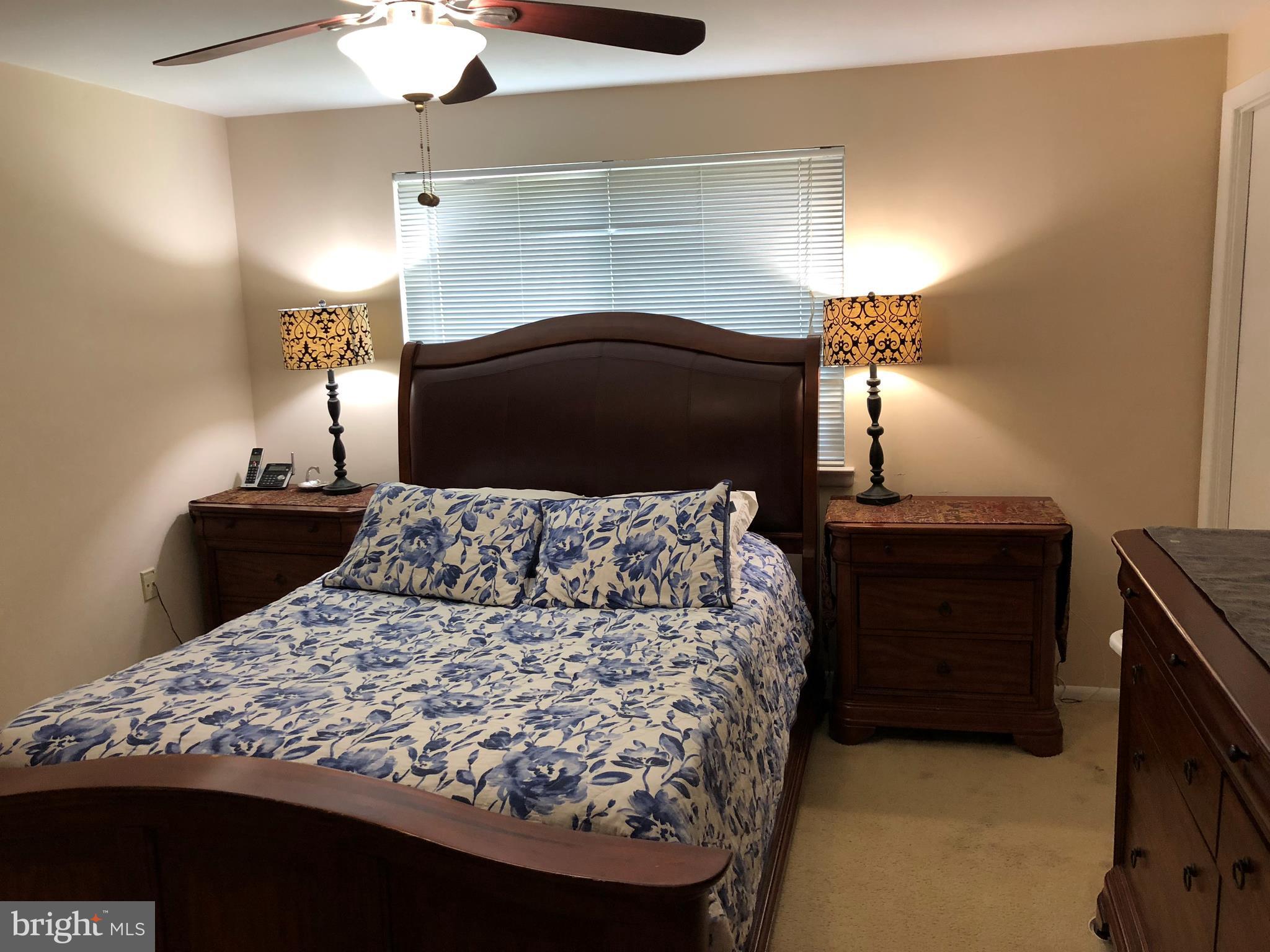 8989 Centerway Road Gaithersburg, MD 20879 - Photo 3 of 26 a bedroom with a bed and a lamp on dresser