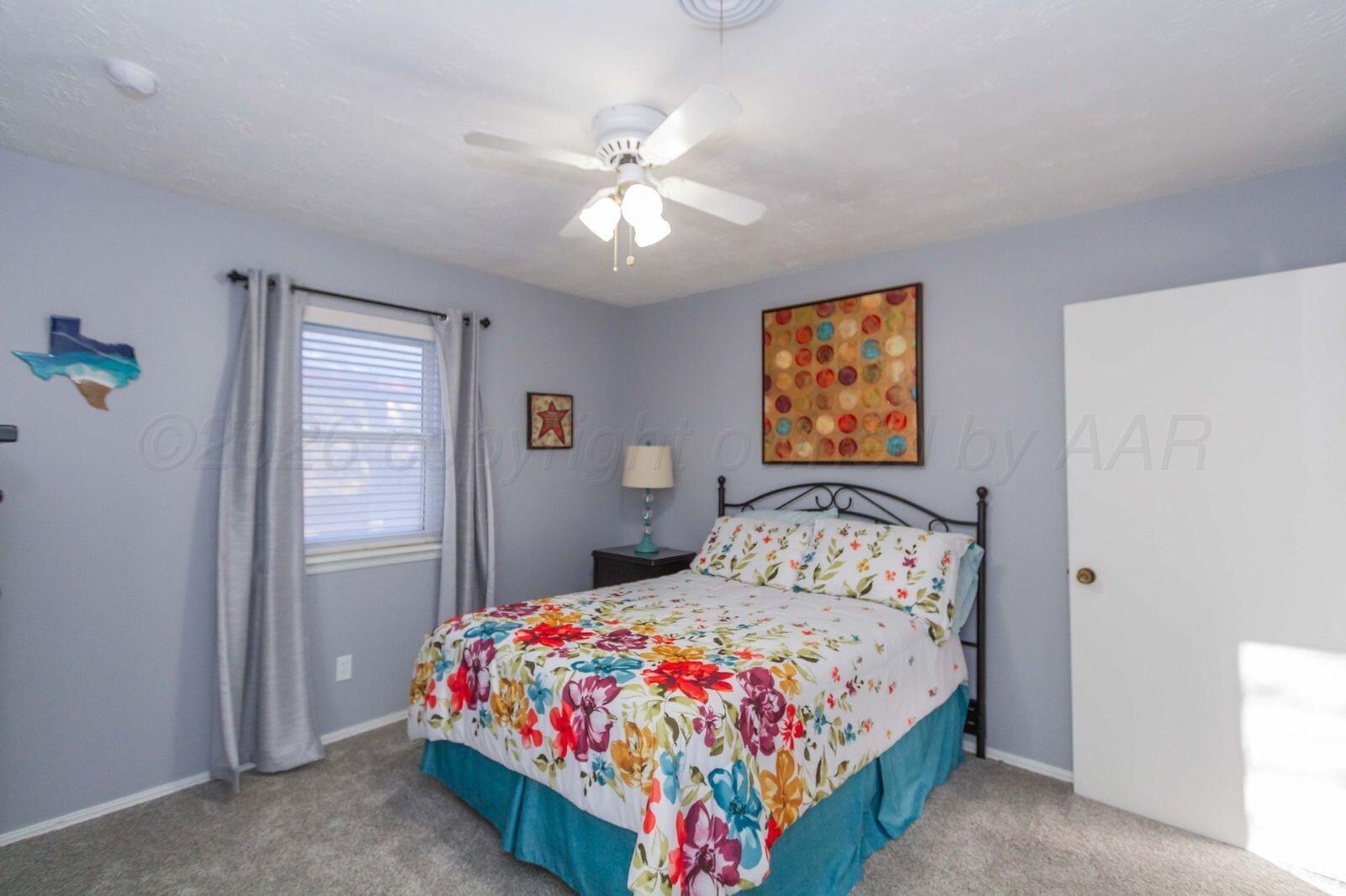 7612 Farrell Drive Amarillo, TX 79121 - Photo 18 of 27 a bedroom with a bed and a chandelier