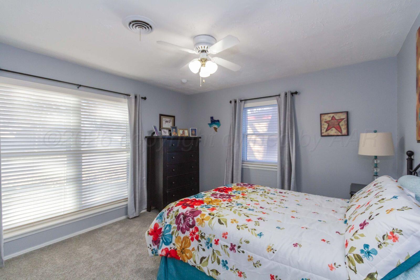 7612 Farrell Drive Amarillo, TX 79121 - Photo 19 of 27 a bedroom with a bed and a chandelier