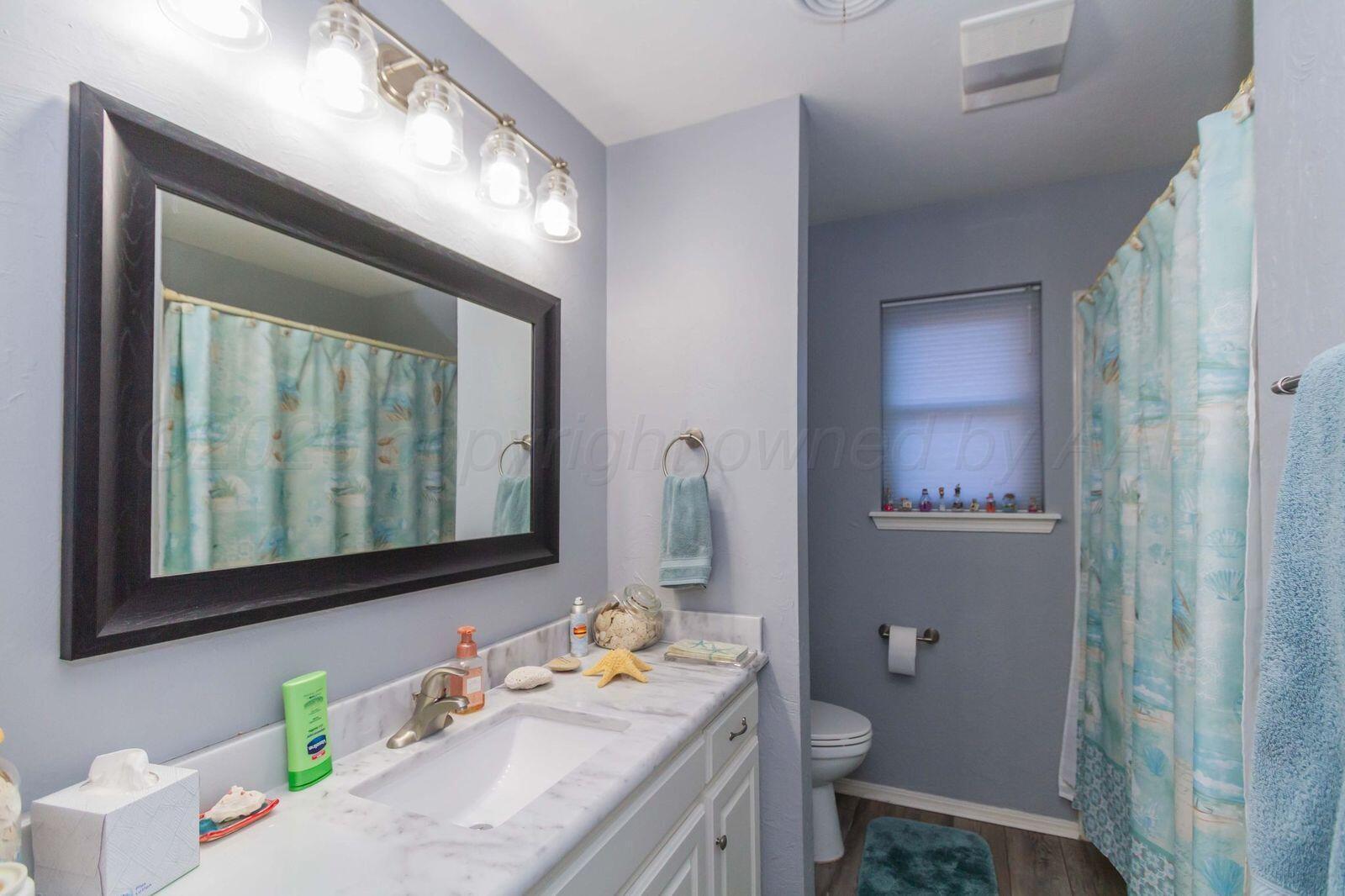 7612 Farrell Drive Amarillo, TX 79121 - Photo 21 of 27 a bathroom with a granite countertop sink a toilet and a mirror