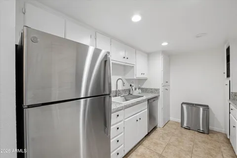 a kitchen with stainless steel appliances granite countertop a refrigerator sink and white cabinets