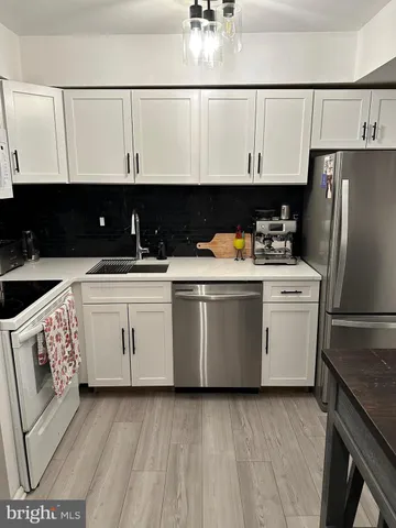 a utility room with stainless steel appliances granite countertop a stove a refrigerator and a sink