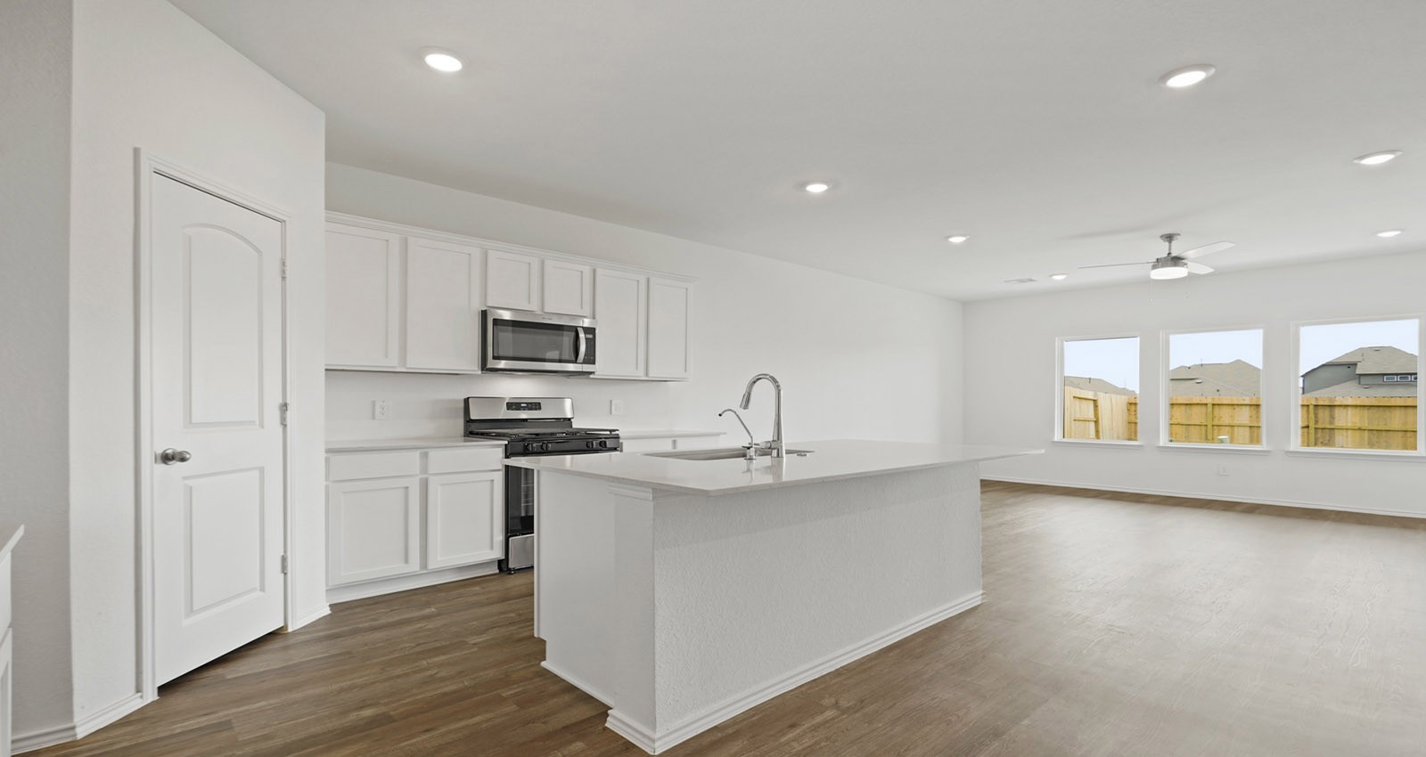 31722 Melkridge Road Fulshear, TX 77441 - Photo 5 of 20 a kitchen with stainless steel appliances granite countertop a stove a sink a refrigerator and white cabinets with wooden floor