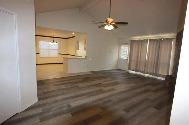 an empty room with wooden floor and fan