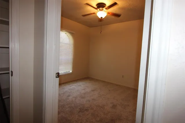 an empty room with windows and fan