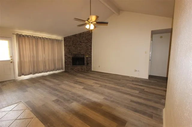 an empty room with a fireplace and chandelier fan