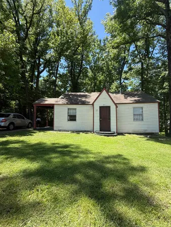 a front view of a house with a yard and trees