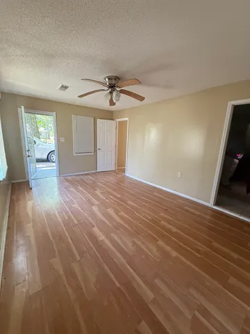 a view of empty room with wooden floor and fan