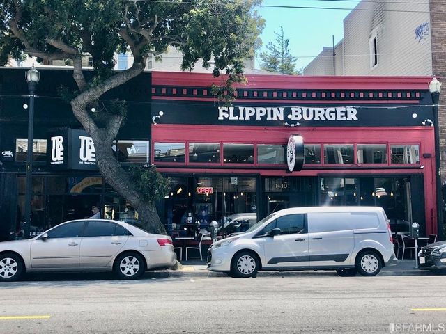 a front view of a building with lots of green space and plants