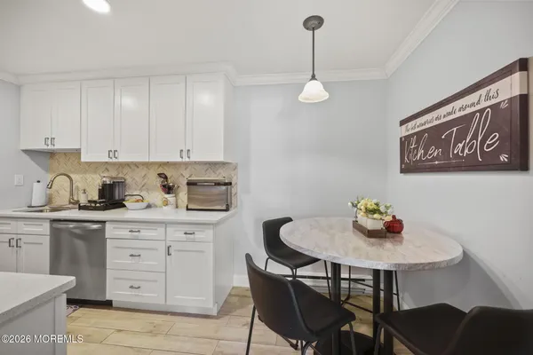 a kitchen with stainless steel appliances granite countertop a sink white cabinets and chairs