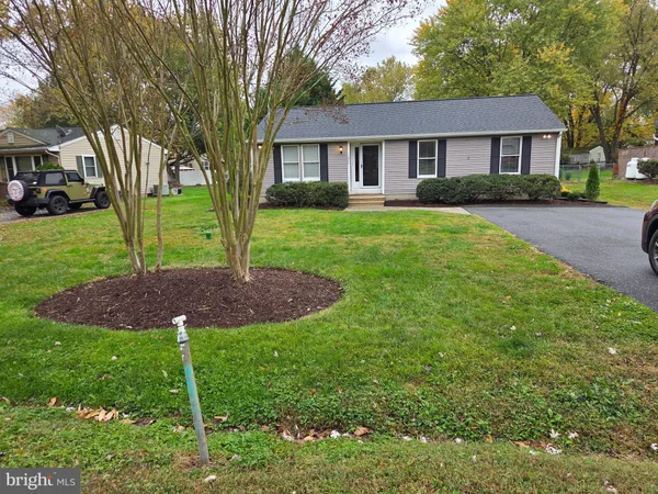 a view of house in front of a big yard with large trees