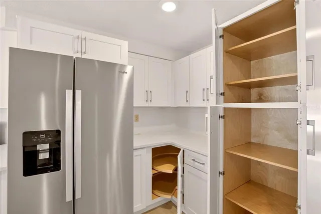 a view of a livingroom with a ceiling fan a kitchen space with wooden floor and a ceiling fan