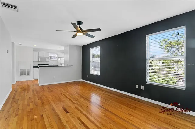 a view of empty room with wooden floor and fan