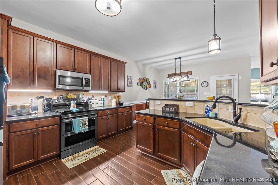 667 St Johns Loop Raeford, NC 28376 - Photo 16 of 50 a kitchen with stainless steel appliances granite countertop wooden cabinets a sink a stove a dining table and chairs