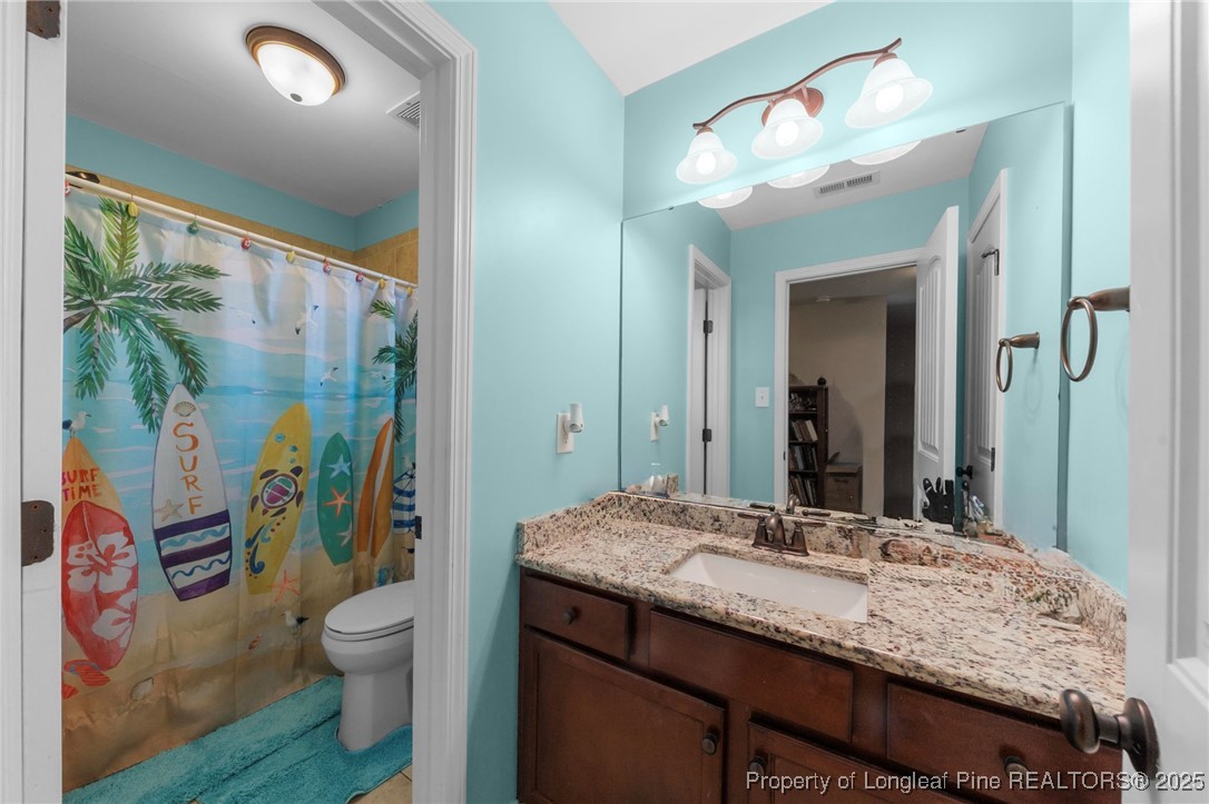 667 St Johns Loop Raeford, NC 28376 - Photo 41 of 50 a bathroom with a granite countertop sink a toilet a mirror a vanity and shower
