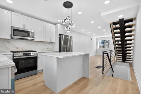 a kitchen with stainless steel appliances granite countertop a stove top oven a sink a counter space and cabinets