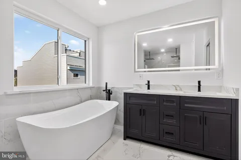 a bathroom with a tub a sink and mirror