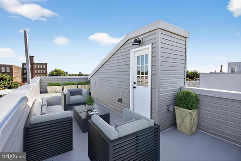 a roof deck with couches and potted plants