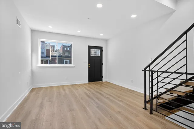 a view of an empty room with wooden floor and stairs