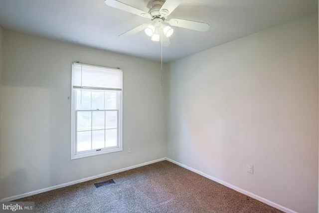 an empty room with windows and chandelier fan