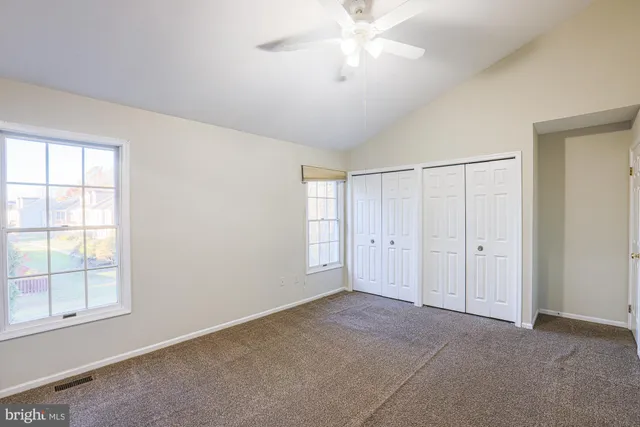 an empty room with windows and fan