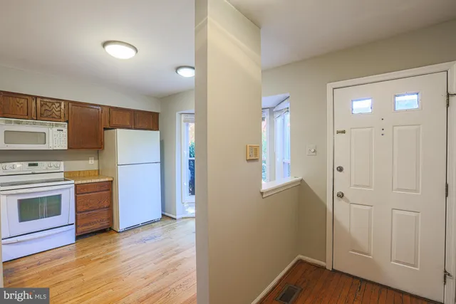 a view of a kitchen with a refrigerator a stove top oven and cabinets