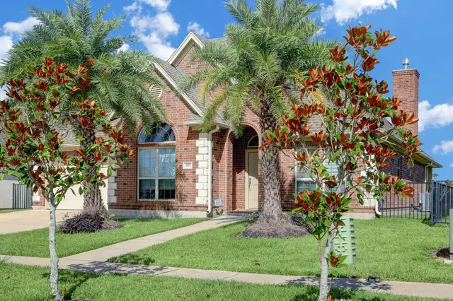 a front view of a house with a garden and trees