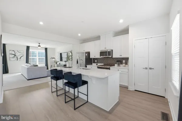 a living room with furniture a dining table and kitchen view with wooden floor