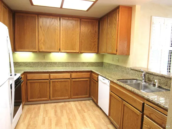 a kitchen with granite countertop a sink window and cabinets