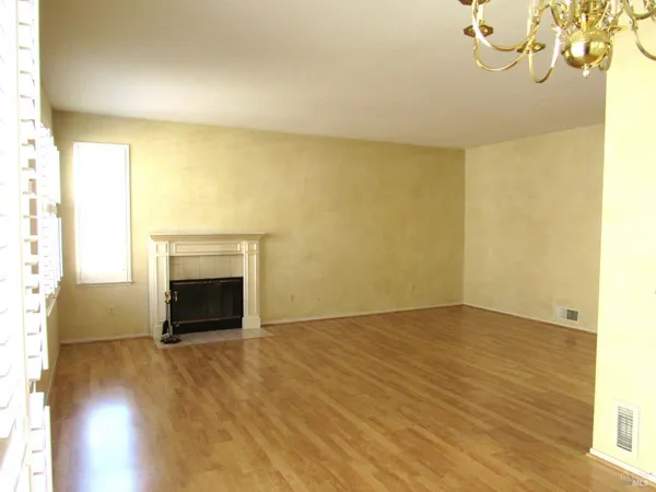 a view of empty room with wooden floor and a fireplace