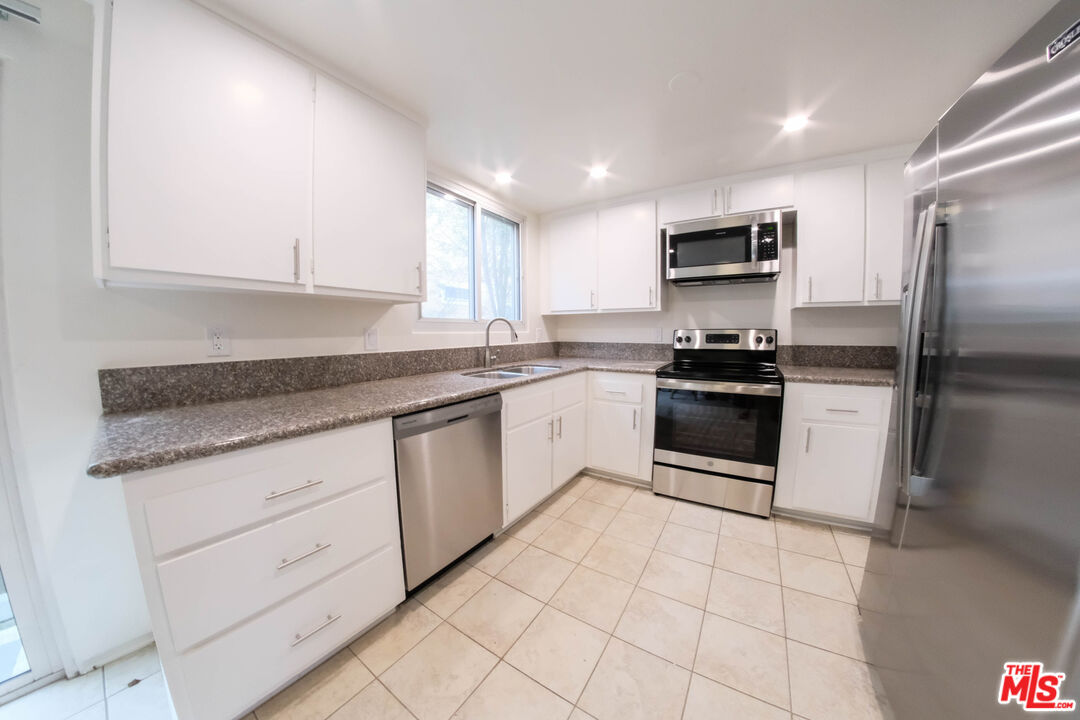 a kitchen with stainless steel appliances granite countertop a stove a sink and a refrigerator