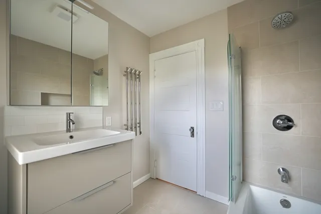 a bathroom with a tub sink a mirror a shower and vanity