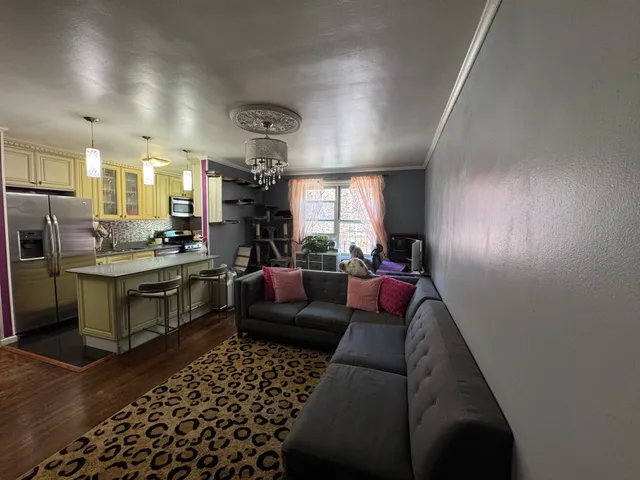 a living room with furniture a rug kitchen view and a chandelier