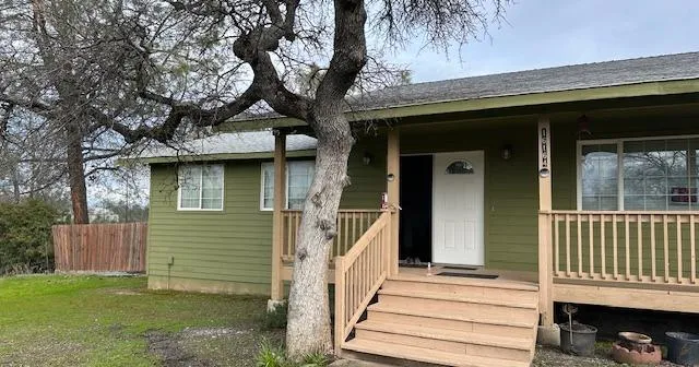 a view of a house with a small yard next to a large tree