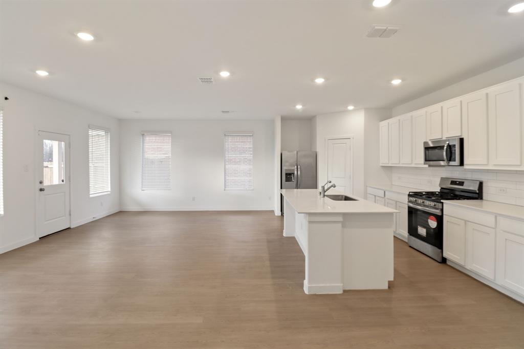 1016 Flameleaf Drive Princeton, TX 75407 - Photo 30 of 32 Kitchen featuring stainless steel appliances, white cabinetry, a kitchen island with sink, recessed lighting, and open floor plan